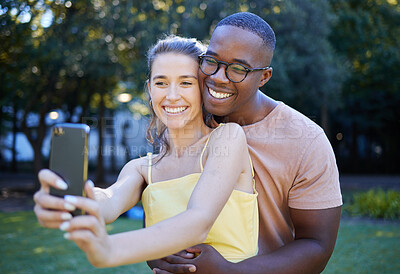 Buy stock photo Selfie, phone and interracial couple hug in park enjoying weekend, summer holiday and quality time together. Nature, dating and happy man and woman take picture on smartphone relax, calm and freedom