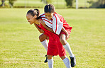 Girl soccer player, happy celebration and grass with piggyback for goal, teamwork and winning contest. Young female kids, winner and celebrate with support, solidarity and happiness at soccer field