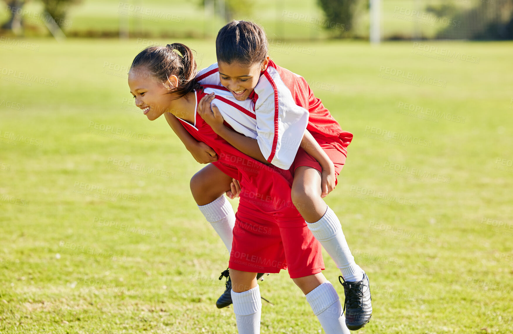 Buy stock photo Girl soccer player, happy celebration and grass with piggyback for goal, teamwork and winning contest. Young female kids, winner and celebrate with support, solidarity and happiness at soccer field
