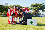 Sports, first aid and children soccer team with an injury after a game in a huddle helping a girl athlete. Fitness, training and kid with a sore, pain or muscle sprain on an outdoor football field.