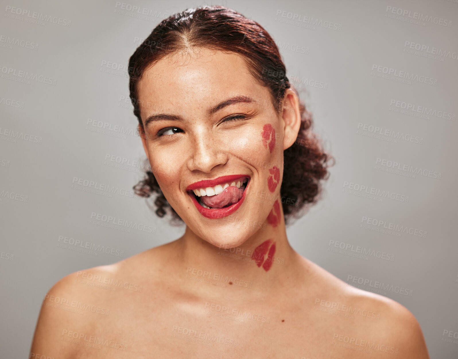 Buy stock photo Beauty, face and woman lipstick and wink with kiss print on skin, flirt and sexy, tongue out isolated on studio background. Red, lips and smile with skincare, makeup mockup, fun and cosmetic care