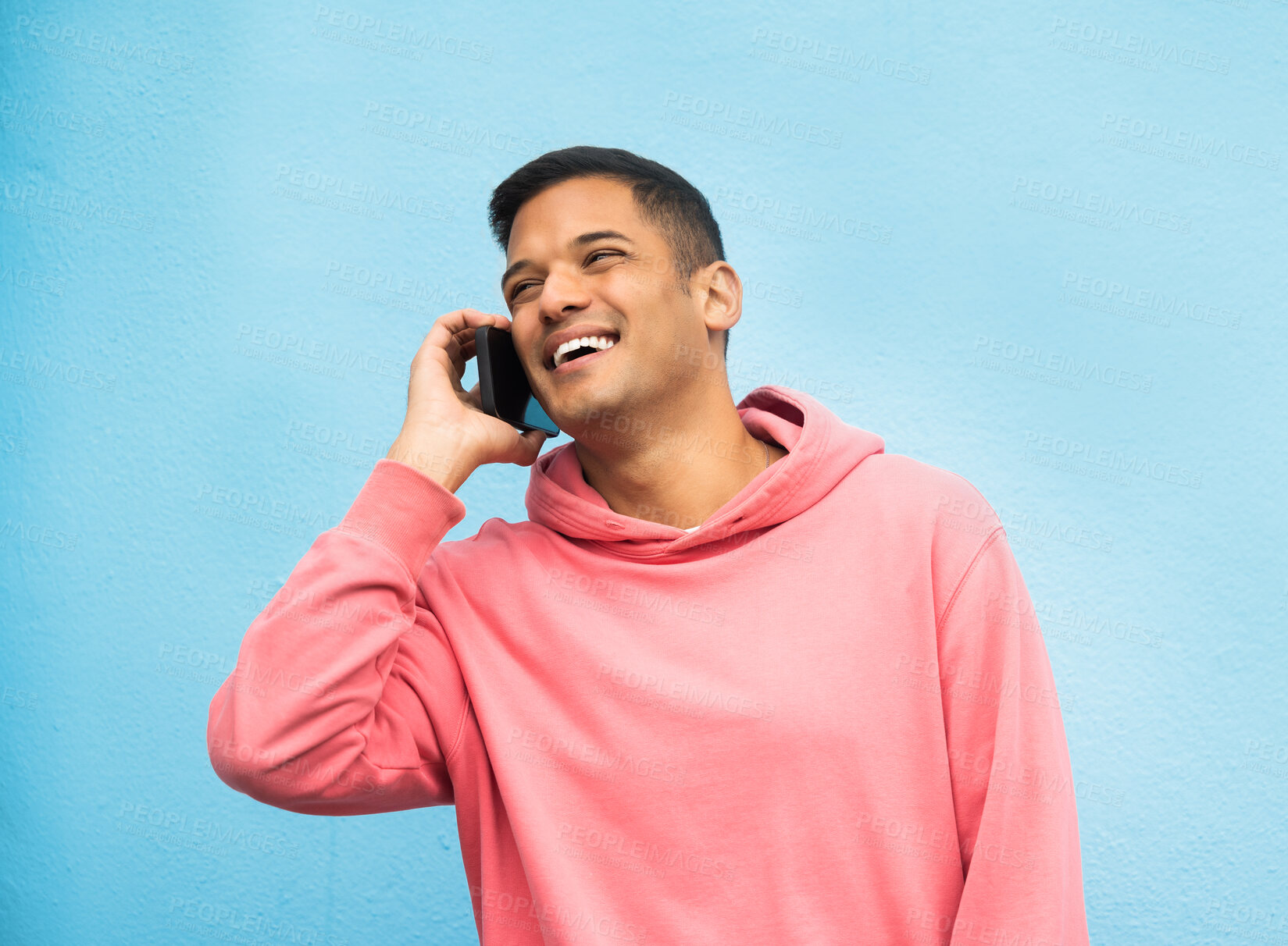 Buy stock photo Casual man, phone call and laughing in communication standing isolated on a blue background. Happy male, person or guys with pink jacket in discussion, conversation or talking on mobile smartphone