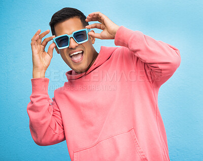 Buy stock photo Happiness, man with sunglasses and smile with face, trendy fashion and happy with freedom isolated on blue background. Funky, retro and wellness, hipster person in studio with vintage designer brand