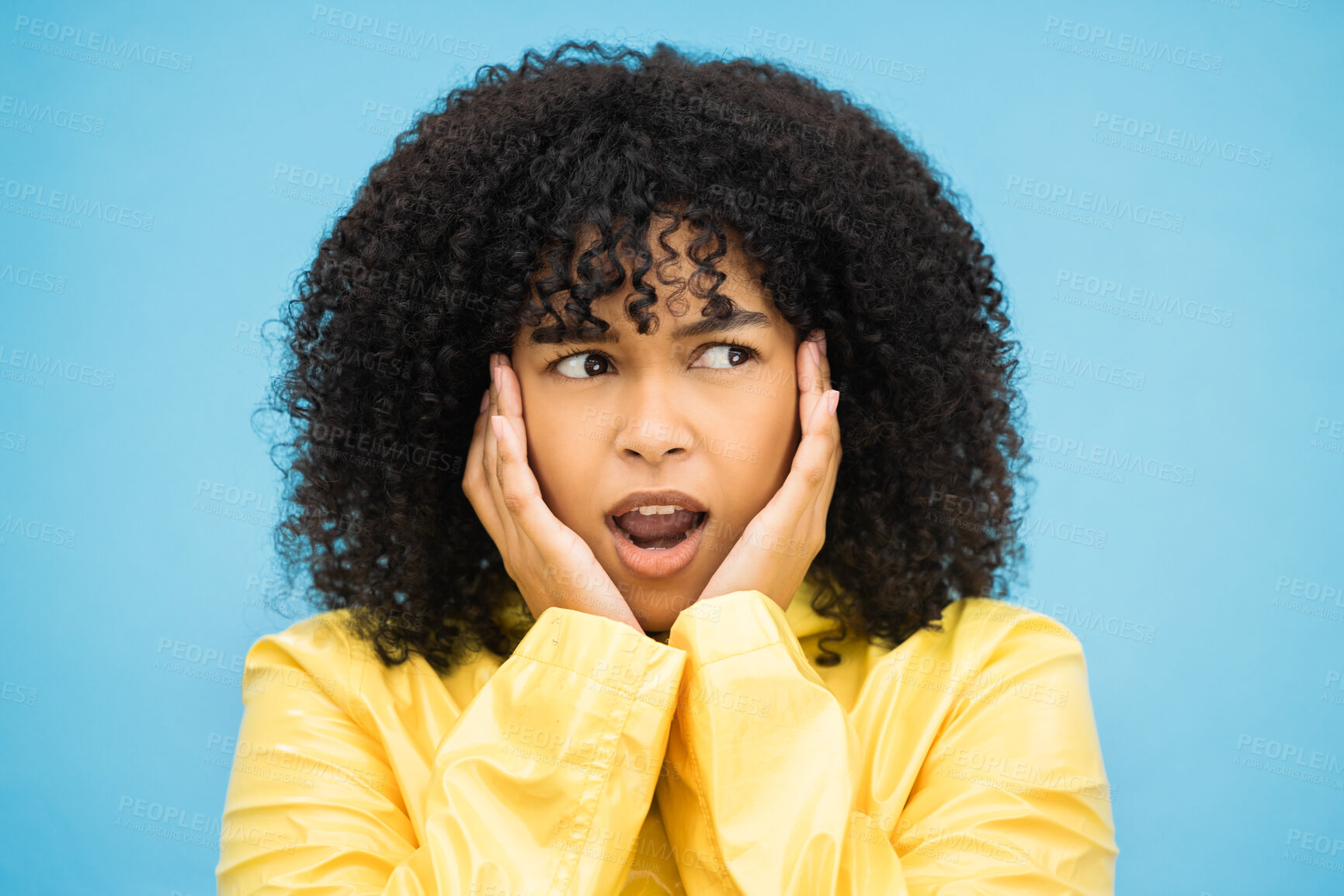 Buy stock photo Black woman, afro or shocked face on isolated blue background in raincoat weather change, rainfall or rain. Model, person or surprised student with hands on cheeks in wow, emoji or scared expression
