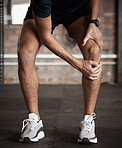 Knee injury, pain and fitness with a sports man holding his joint during a workout routine in the gym. Anatomy, accident and exercise with a male athlete injured while training in a health club