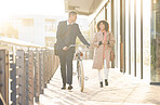 Business couple, bicycle and walking outdoor in urban city for freedom, relax conversation and travel commute. Businessman, woman smile and happy speaking together on bike walk for carbon footprint