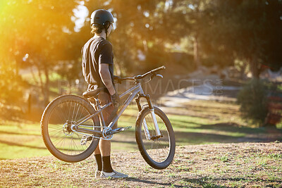 Bike, fitness and summer with a sports man outdoor in nature for leisure or recreation in summer. Back, bicycle and exercise with a male athlete standing on an open green field carrying his transport