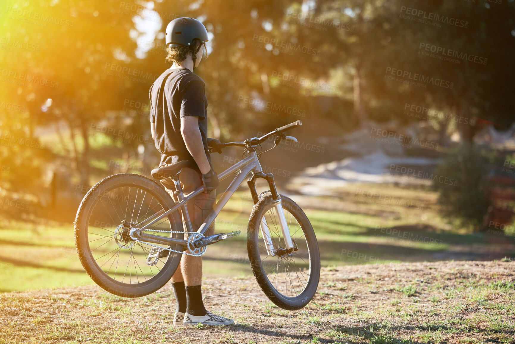 Buy stock photo Bike, fitness and summer with a sports man outdoor in nature for leisure or recreation in summer. Back, bicycle and exercise with a male athlete standing on an open green field carrying his transport