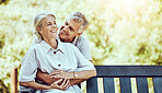 Love, nature and elderly couple hugging while sitting on an outdoor bench in the park. Happy, care and senior man embracing his wife in retirement on romantic date together in green garden in Canada.