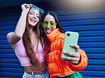 Fashion, selfie and friends with phone on blue background with style, cool sunglasses and urban clothes. Social media, smartphone and women smile for photo on weekend, vacation and holiday in city