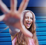 Music, dance and wink with a woman reaching on a blue background while listening to the radio. Freedom, fun and audio with an attractive young female streaming a playlist or song while dancing