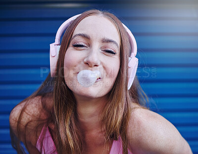 Buy stock photo Girl, bubblegum and headphones, face in portrait isolated on blue background, listen to music with freedom and fashion. Blow bubble, candy and crazy gen z youth in studio, fun with radio or audio