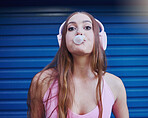 Young woman, bubblegum and headphones, face isolated on blue background, listen to music with freedom and fashion. Blowing bubble, candy and crazy gen z youth in studio, fun with radio or audio tech