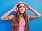 Music, headphones and blue background with a woman streaming or listening to audio for fun. Radio, internet and 5g with an attractive young female using wireless technology to listen to a song