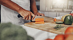 Hands, food and nutrition with a man cooking in the kitchen while cutting vegetables on a wooden chopping board. Salad, health or diet with a chef preparing a meal while standing alone in his home