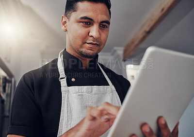 Buy stock photo Man with apron, focus and tablet for online recipe, cooking instructions and connection in kitchen. Male, chef and gentleman with device, communication and search for ingredients, thinking and ideas