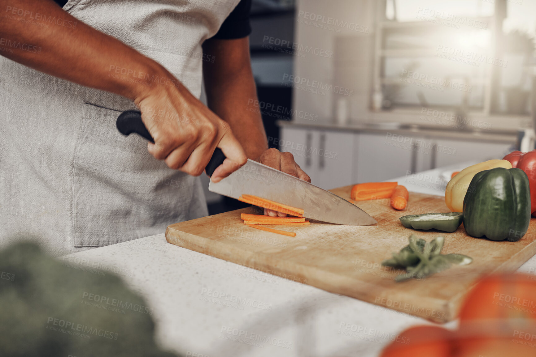 Buy stock photo Hands, food and salad with a man cooking in the kitchen, while cutting carrots on a wooden chopping board. Nutrition, health or diet with a male chef preparing a meal while standing alone in his home