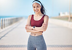 Happy woman, portrait and fitness with arms crossed at beach promenade for exercise, wellness and health in Miami. Female athlete, smile and standing at seaside for workout, summer training or sports