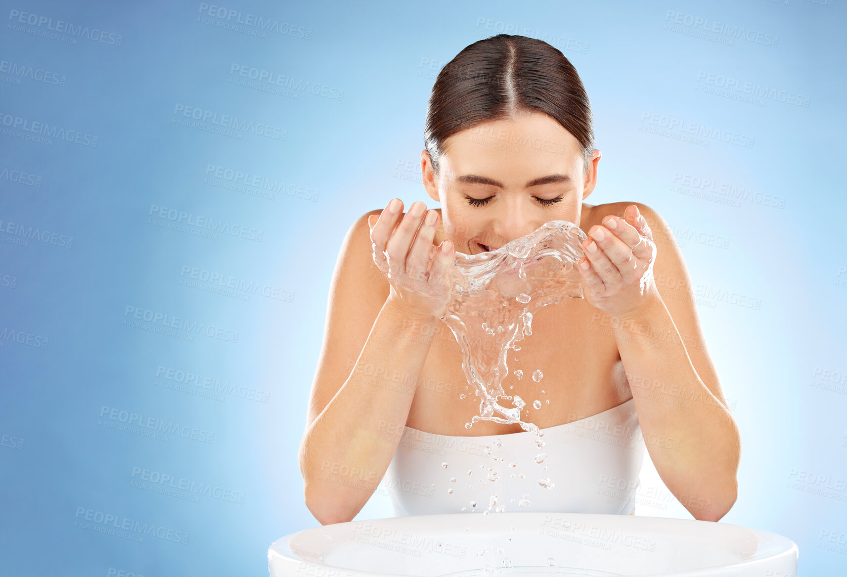 Buy stock photo Woman, beauty and water splash for clean face or skin with natural dermatology cosmetic product. Happy aesthetic model in studio for health and wellness or self care spa facial on blue background