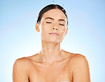Shower, water and woman cleaning skin for beauty and cosmetic skincare isolated in a studio blue background. Facial, splash and female model washing as body care for hygiene, dermatology and wellness