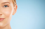 Skincare, smile and half portrait of a woman for dermatology isolated on a blue background. Makeup, wellness and face of a model for cosmetics, health and collagen with mockup space on a backdrop