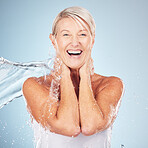 Portrait, senior woman and water splash for dermatology, cosmetics and skincare on grey studio background. Face, mature female or elderly lady wet, smile or cleaning for hygiene, healthy or soft skin