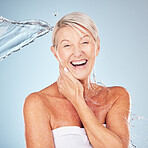 Smile, shower and portrait of a woman with a water splash isolated on a blue background in studio. Grooming, hygiene and face of an excited senior model with body and self care on a backdrop
