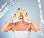 Water splash, studio and woman with lemon for wellness, healthcare or vitamin c by blue background. Happy senior model, citrus fruit and cosmetic skincare for happiness, excited or water drop on skin
