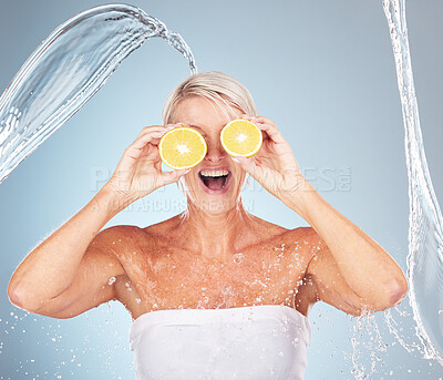 Buy stock photo Water splash, studio and woman with lemon for wellness, healthcare or vitamin c by blue background. Happy senior model, citrus fruit and cosmetic skincare for happiness, excited or water drop on skin