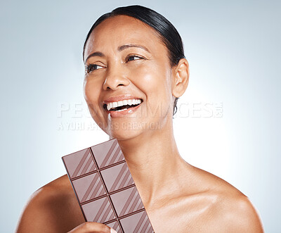 Buy stock photo Chocolate, smile and senior woman thinking of health isolated on a blue background in studio. Food, happy and face of an elderly model with an idea for candy, sugar snack and sweets on a backdrop