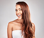 Hair care, beauty and portrait of a woman in studio for a keratin, brazilian or botox hair treatment. Happy, smile and female model with a wavy, long and shiny hair style isolated by gray background.