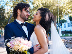 Interracial love and couple wedding with flowers for romantic outdoor marriage event celebration together. Partnership, commitment and trust embrace of happy bride and groom with excited smile.
