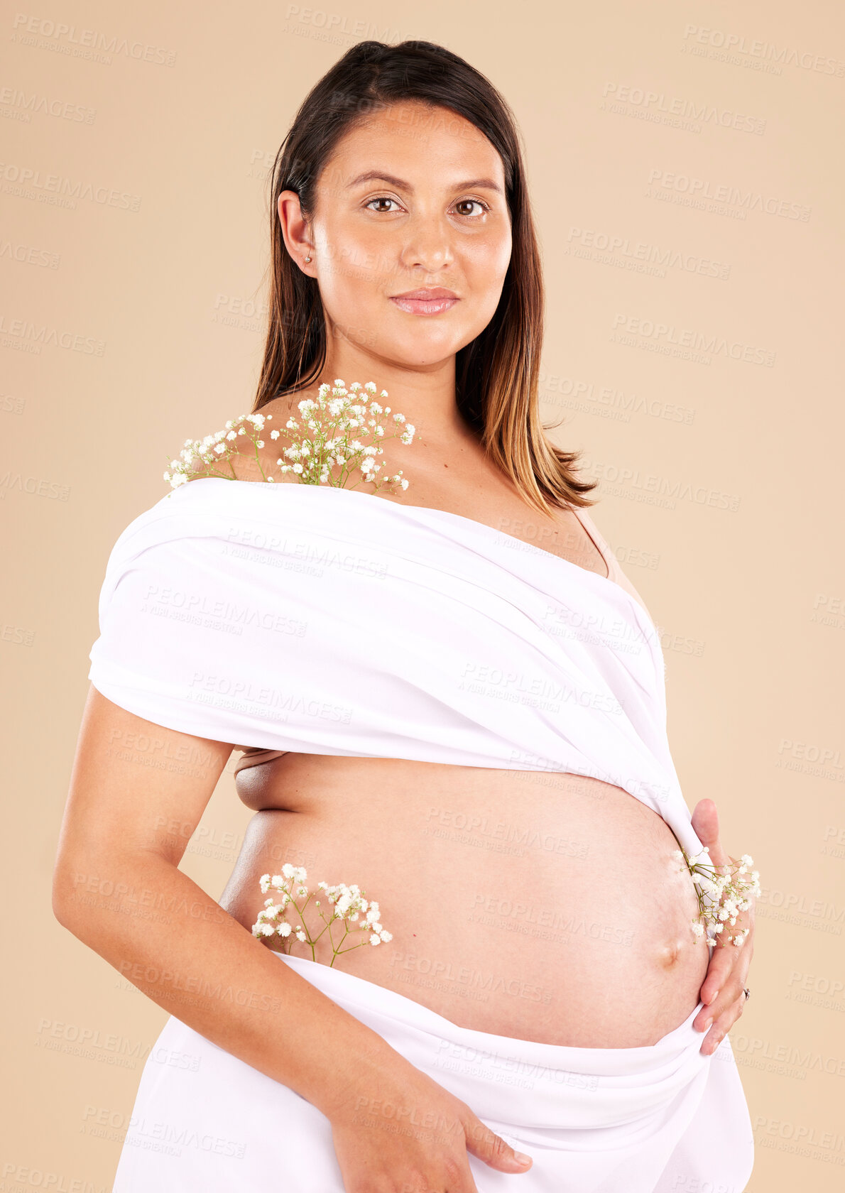 Buy stock photo Pregnancy, flowers and portrait of a woman in studio with chiffon material on her body holding her stomach. Maternity, prenatal health and pregnant female model with floral posing by beige background