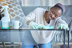 Cleaning, table and black woman with cloth in home for dirt, dust and bacteria on furniture. Happy cleaner, housekeeping and maid wipe surface in living room for routine maintenance, safety and care