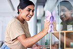 Happy, woman and cleaning home window with household cloth and satisfied smile for shiny transparent surface. Happiness, focus and concentration of young indian girl polishing glass in house. 