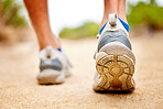 Fitness, shoes and sports person walking, running and man training on path. Back closeup of runner, feet and sneakers on ground for exercise, park workout and outdoor trekking, hiking and wellness 