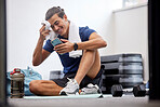 Fitness, phone or man with fatigue on social media at gym in training, workout or exercise resting on a break. Tired, smile or healthy sports athlete relaxing on a mat after exercising for body goals