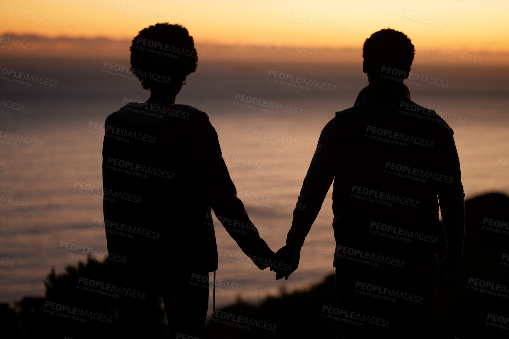 Buy stock photo Sunset, beach and silhouette of couple holding hands for date by the sea with dark shadow, love and care. Horizon, ocean and people rear with together in nature for hiking or travel goals on holiday