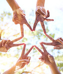 Hands together, star sign and team sun gesture with hand to show group work and community. Outdoor, lens flare and below of people doing teamwork with friends showing commitment and solidarity 