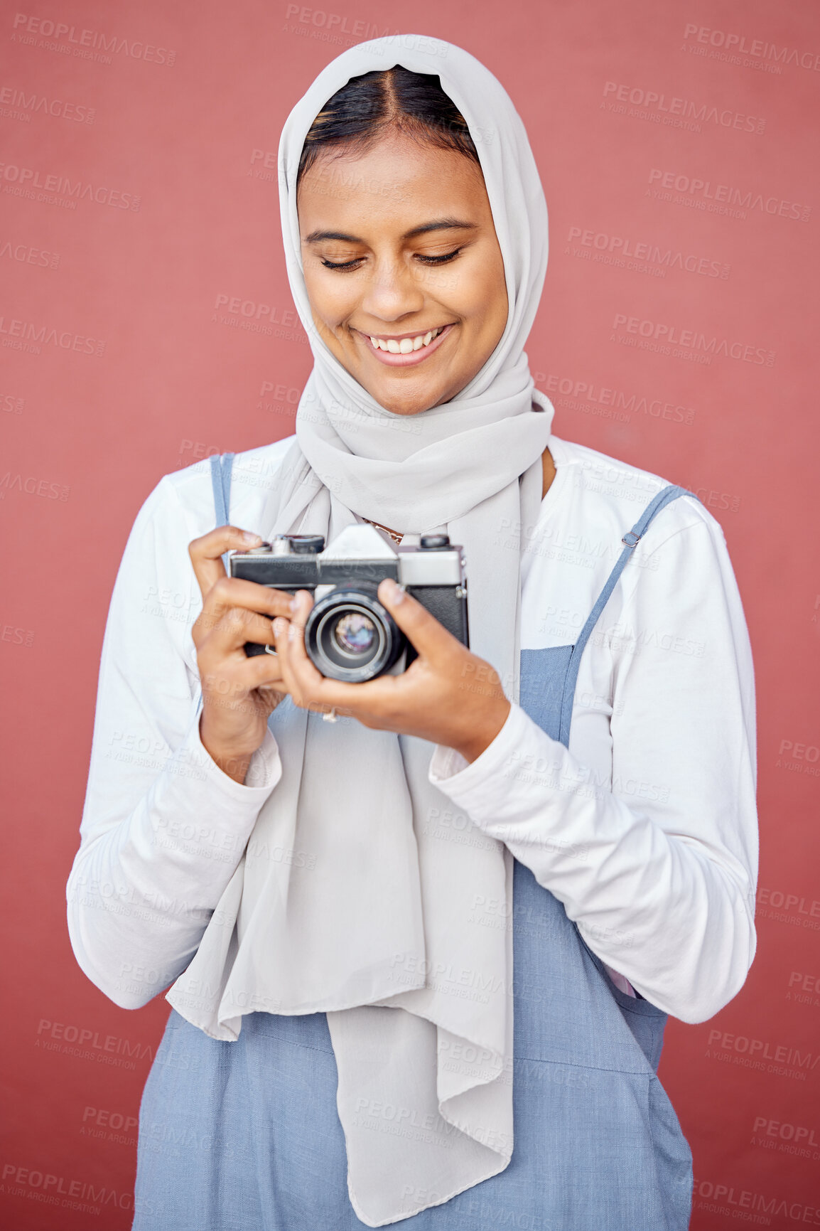 Buy stock photo Muslim, hijab and photographer shooting a picture or photo with a retro camera isolated in a studio red background. Islam, Dubai and woman in scarf happy taking creative shots for photography