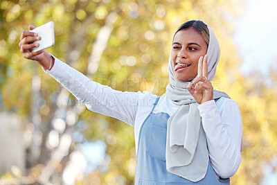 Buy stock photo Selfie, peace and Islamic woman outdoor, silly face or confident with casual outfit, happiness or joy. Muslim female, lady in nature or smartphone to share photo, social media or connection with sign