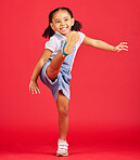 Happy, kick and excited girl in a studio with a casual, stylish and fashion kid outfit. Happiness, smile and young child with cool clothes kicking her leg with excitement isolated by a red background