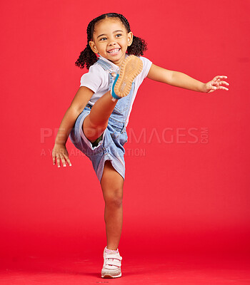 Buy stock photo Happy, kick and excited girl in a studio with a casual, stylish and fashion kid outfit. Happiness, smile and young child with cool clothes kicking her leg with excitement isolated by a red background