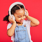Happy, child and headphones for music, radio and fun podcast on isolated red background and dancing studio. Smile, little girl and kid listening to dance audio, song and streaming media on backdrop