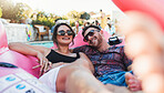 Couple, relax and smile for pool party on inflatable floating in the water enjoying summer vacation together. Happy man and woman relaxing in swimming pool on floaty with sunglasses for holiday break