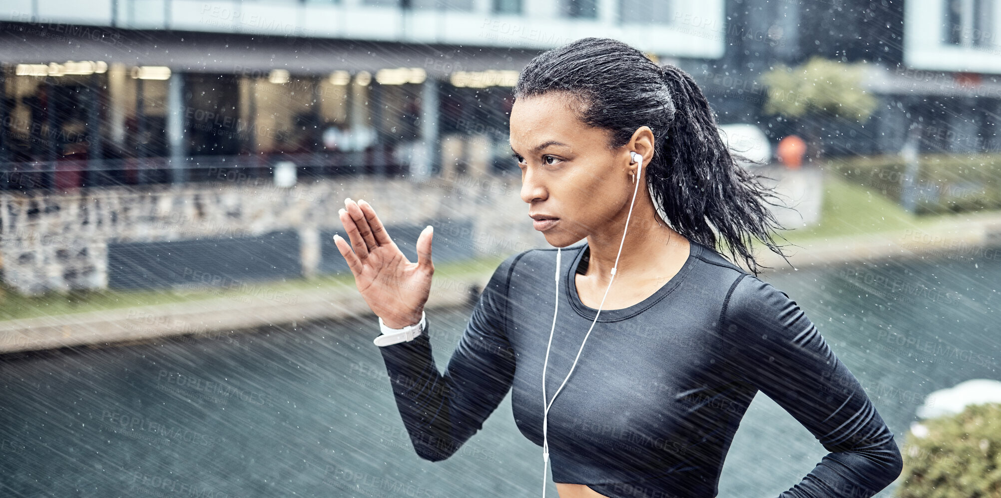 Buy stock photo Black woman, fitness and running with earphones in the rain for sports motivation or determination in the city. African American sporty female runner doing intense cardio workout in the rainy weather