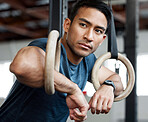 Thinking, gymnastic rings and olympics with a man gymnast hanging on equipment for workout in gym. Idea, fitness and exercise with a male athlete training in gymnastics for health or power