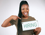 Creative business woman, pointing and hiring sign for recruiting isolated on gray studio background. Portrait of happy African American female manager with board for recruitment, job hire or startup