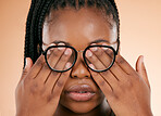 Hands, eye health or glasses with a black woman in studio on a beige background covering her face. Vision, blind and cover with a female indoor to promote eyecare or health for the optometry industry