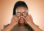 Hands, eyes and glasses with a black woman in studio on a beige background covering her face. Vision, blind and cover with a female indoor to promote eye care or health for the optometry industry